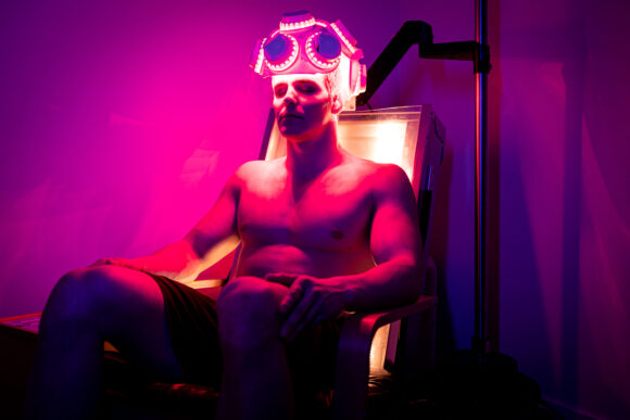 Person using the SunPowerLED transcranial helmet for Red Light therapy at home, targeting brain health and cognitive support.