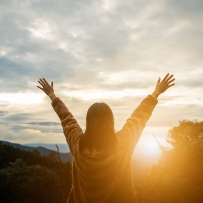 Woman Embracing a New Beginning with Arms Raised at Sunrise