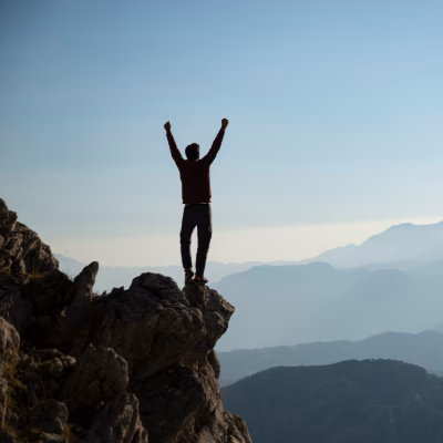 Man Standing on a Mountain Peak, Symbolizing Success and Personal Growth